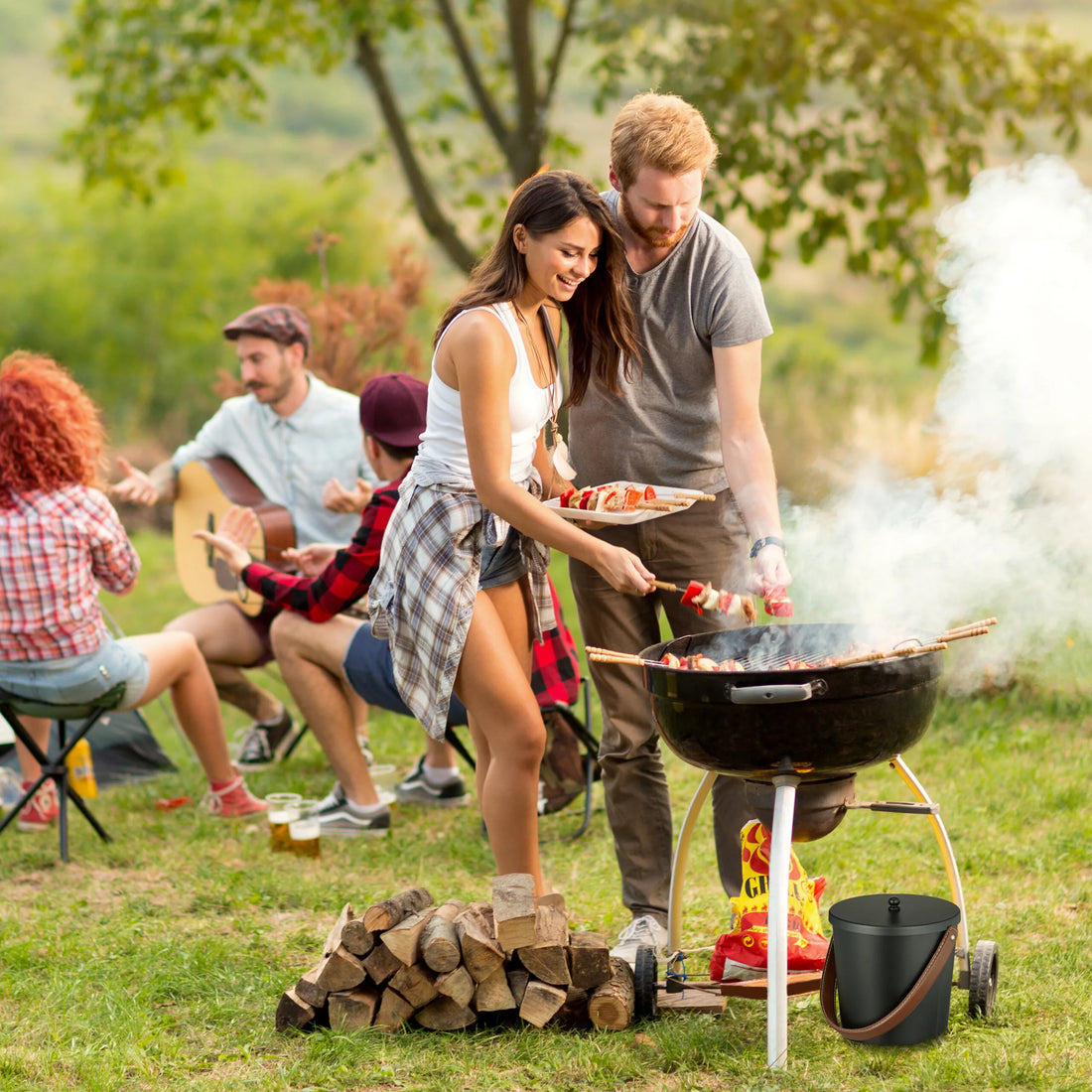 Ascheeimer neben einem Holzkohlegrill bei einem Picknick mit Freunden im Garten