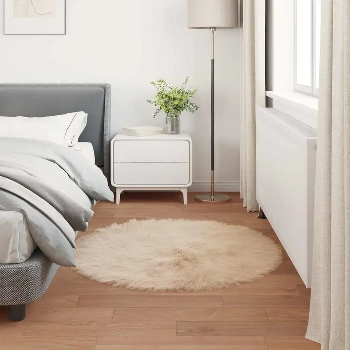 Teppich rund aus Kunstfell in Beige vor dem Bett im hellen Schlafzimmer mit Holzboden