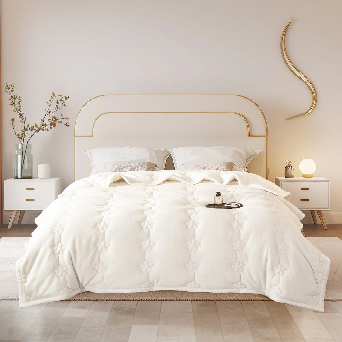 Steppdecke in Creme-Beige mit Blütensteppung auf einem Bett mit goldenem Kopfteil