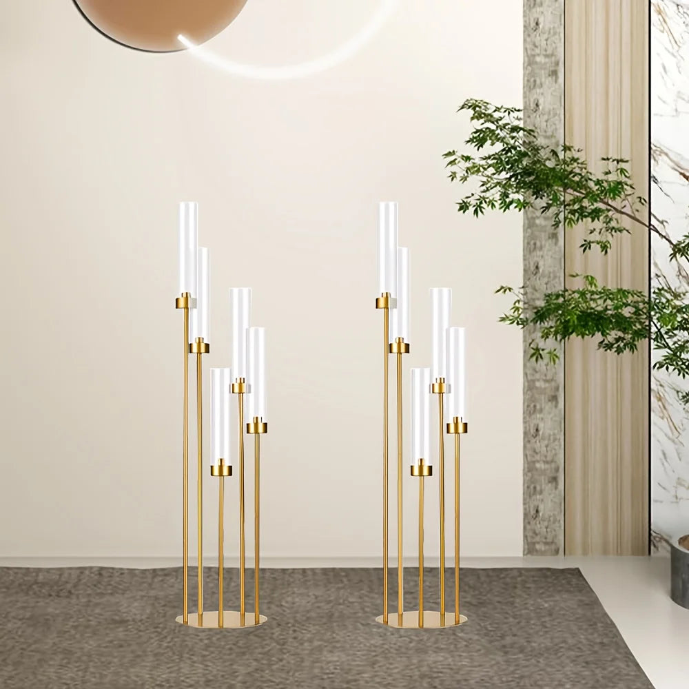 Zwei Boden-Kerzenständer in Gold mit Glasschirmen im hellen Raum neben einer Grünpflanze