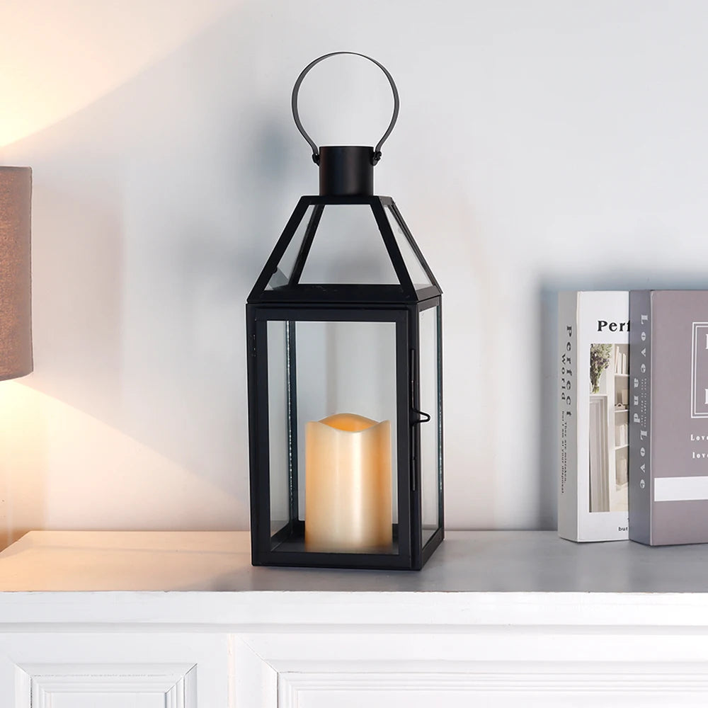 Moderne Laterne in Schwarz mit Kerze auf einem weißen Sideboard neben Büchern