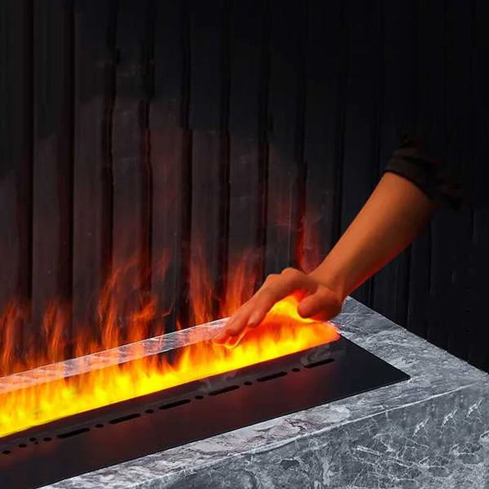 Hand greift in die kühle Nebelflamme eines eingebauten Elektrokamins mit Einfassung in grauer Marmoroptik