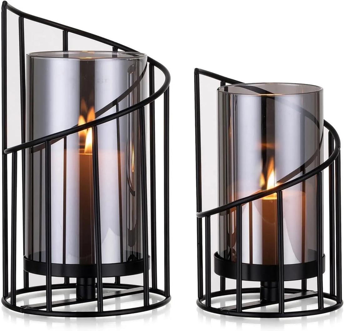 Zwei schwarze Windlichter mit spiralförmigem Metallrahmen und Rauchglas, Kerzen brennen