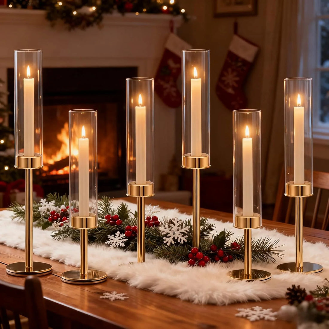 Sechs Kerzenständer aus Glas und Gold auf weihnachtlichem Tischläufer vor brennendem Kamin