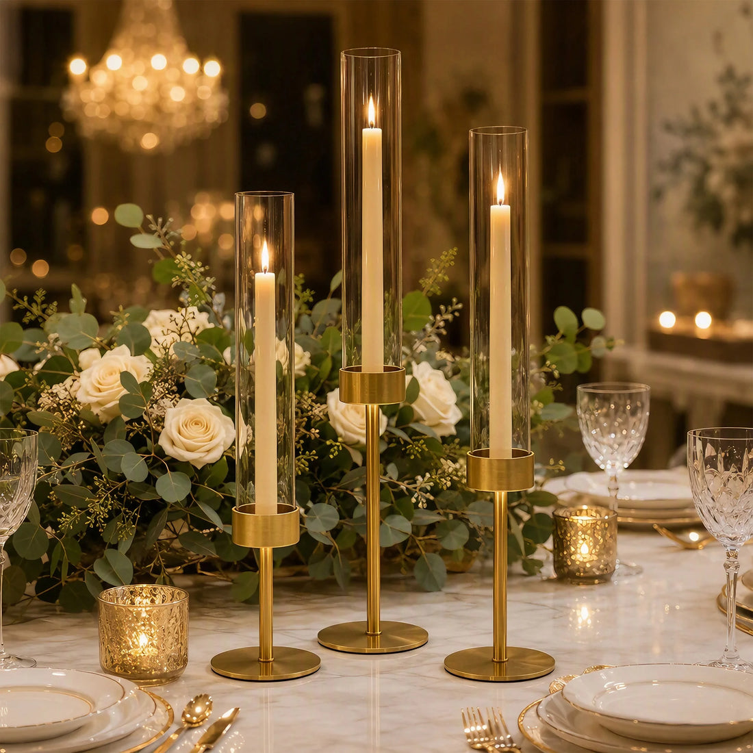 Goldene Kerzenhalter mit Stabkerzen zwischen Rosen auf festlicher Tafel unter Kronleuchter