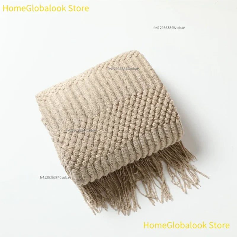 Zusammengelegte Strickdecke mit Quasten in Khaki auf weißem Hintergrund