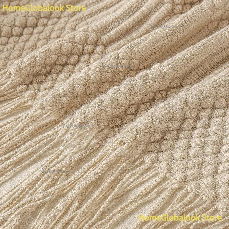 Quasten und Strickmuster der khakifarbenen Wohndecke im Detail