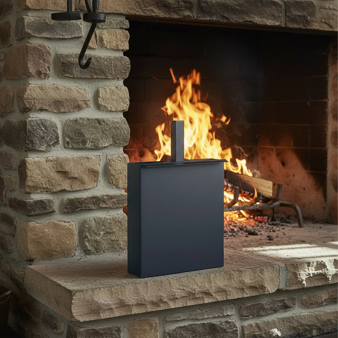 Ascheeimer mit eingesteckter Schaufel auf dem Kaminsockel vor einem brennenden Feuer