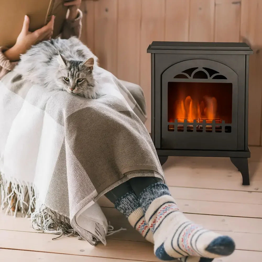 Schwarzer Bioethanol-Kamin in Ofenoptik auf Holzboden, davor Person mit Decke und Katze